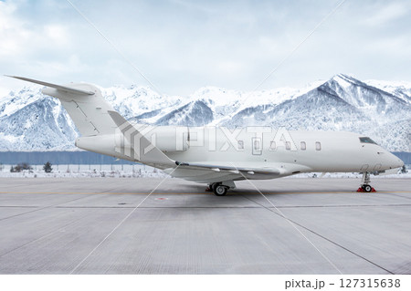 Luxury white private aircraft at the airport on the background of high picturesque snow capped mountains Luxury white private aircraft at the airport on the background of high picturesque snow capped mountains 127315638