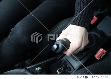 Engaging the handbrake inside a vehicles interior, showcasing dynamic interaction and safety 127315656
