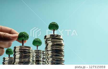 Hand putting Mini trees to growing on coin stacks symbolizing sustainable investment, green finance, and eco-friendly economic growth Hand putting Mini trees to growing on coin stacks symbolizing sustainable investment, green finance, and eco-friendly economic growth 127315959