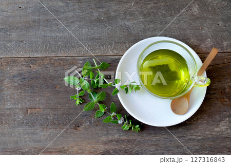 Cup of mint tea and leaves of mint on wood table. 127316843