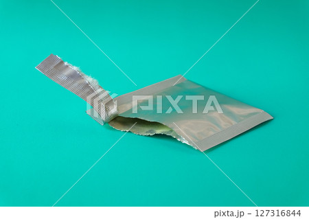 Open aluminum bag lying on color background. 127316844