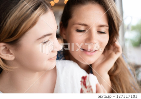 Mother Daughter Bonding Cafe Dessert: Affectionate mother and daughter share dessert at a cafe, enjoying a sweet moment together. 127317103
