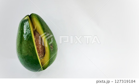 Close-up of a sliced avocado showing the brown seed inside, placed on a clean white surface with soft natural lighting. Close-up of a sliced avocado showing the brown seed inside, placed on a clean white surface with soft natural lighting. 127319184