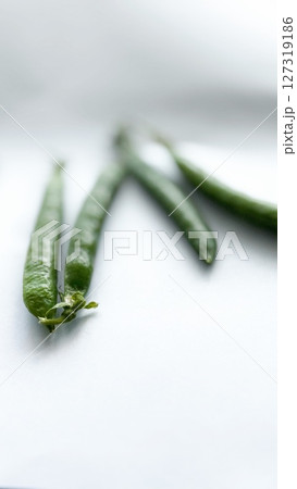 Close-up of fresh green pea pods on a white background with shallow depth of field, ideal for healthy eating concepts. 127319186
