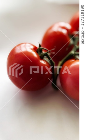 Vine tomatoes standing upright with strong directional lighting creating sharp shadows, emphasizing their red texture and shine. Vine tomatoes standing upright with strong directional lighting creating sharp shadows, emphasizing their red texture and shine. 127319190
