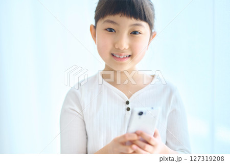 お家でスマホを操作する小学生の女の子 お家でスマホを操作する小学生の女の子 127319208
