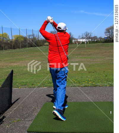 Rear View of a Male Golfer Practicing Swing at Driving Range on a Sunny Day 127319885