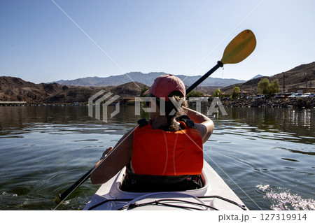 Kayaker Paddling on Calm Water Surrounded by Mountains 127319914