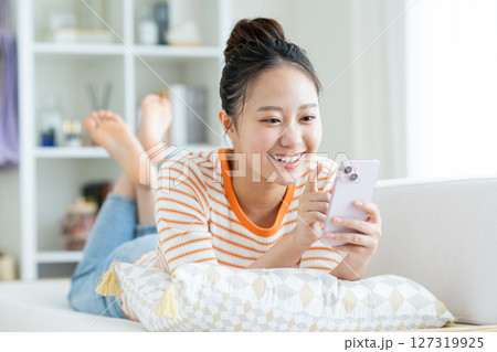 リビングでスマホを見る若い女性 リビングでスマホを見る若い女性 127319925