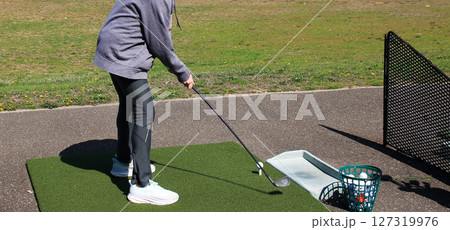 Female Novice Golfer Practicing Swing at Driving Range With Focus on Technique Female Novice Golfer Practicing Swing at Driving Range With Focus on Technique 127319976