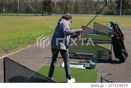 Woman Learning her Golf Swing at a Driving Range on a Sunny Day 127319979