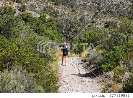 Woman Standing in a Superwomen Pose While Exploring a Rocky Trail 127319981
