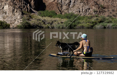 Women Enjoying a Peaceful Day Paddleboarding With a Dog at the Lake 127319982