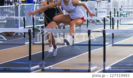 Young Athlete Competes in Hurdle Race at Outdoor Track Event 127319983