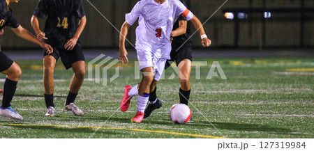 Young Athlete Dribbles Soccer Ball in Night Match 127319984