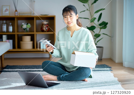 部屋で通販の荷物を確認する若い女性 部屋で通販の荷物を確認する若い女性 127320920