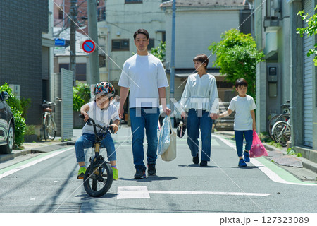 晴天の住宅街を歩く家族4人 127323089