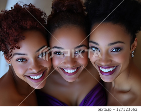 Top view of three smiling African American women with tied-up hair, enjoying a happy moment. Top view of three smiling African American women with tied-up hair, enjoying a happy moment. 127323662