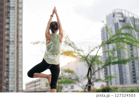 Asian woman in 30s fitness yoga workout. Stretching exercise reduces medical injury risk shoulder pain muscle strain inflammation. Healthy lifestyle wellness healthcare in urban city at sunset Asian woman in 30s fitness yoga workout. Stretching exercise reduces medical injury risk shoulder pain muscle strain inflammation. Healthy lifestyle wellness healthcare in urban city at sunset 127324503