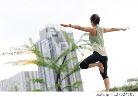 Asian woman 30s fitness yoga workout. Stretching exercise reduces medical injury risk shoulder pain muscle strain inflammation for wellness healthcare healthy lifestyle in urban city at sunset Asian woman 30s fitness yoga workout. Stretching exercise reduces medical injury risk shoulder pain muscle strain inflammation for wellness healthcare healthy lifestyle in urban city at sunset 127324505
