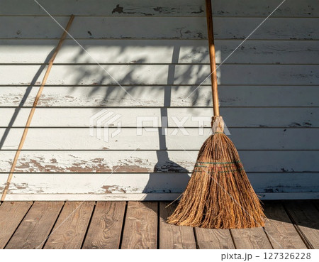Rustic Broom Leaning Against Weathered Wooden Wall 127326228