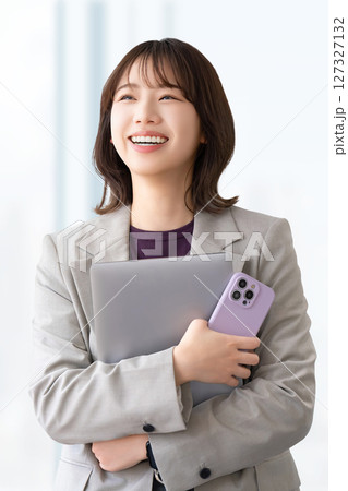 パソコンとスマートフォンを持つ笑顔の女性 127327132