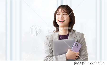 パソコンとスマートフォンを持つ笑顔の女性 127327133