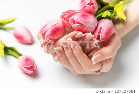Woman holding pink tulips showing french manicure on white background 127327661