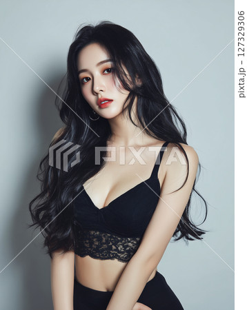 Korean woman poses elegantly in black attire with long hair against a neutral background 127329306