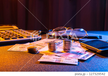 Financial workspace with coins, money, calculator and glasses. Glasses and calculator on the table with money. Finance and accounting. 127329542