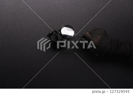 Crumpled paper on the table. A sheet of black crumpled paper on the table. Examine the crumpled sheet under a magnifying glass. Look for details in the trash. 127329545