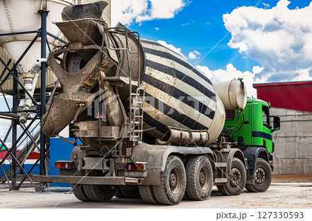 Concrete mixer truck in front of a concrete batching plant, cement factory. Loading concrete mixer truck. Close-up. Delivery of concrete to the construction site. Monolithic concrete works. Concrete mixer truck in front of a concrete batching plant, cement factory. Loading concrete mixer truck. Close-up. Delivery of concrete to the construction site. Monolithic concrete works. 127330593