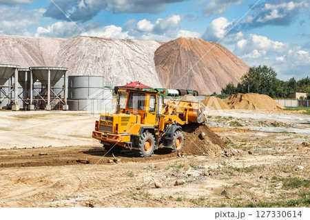 A large front loader pours sand into a pile at a construction site. Transportation of bulk materials. Construction equipment. Bulk cargo transportation. Excavation. 127330614
