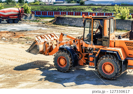 A large front loader transports crushed stone or gravel in a bucket at a construction site or concrete plant. Transportation of bulk materials. Construction equipment. Bulk cargo transportation. A large front loader transports crushed stone or gravel in a bucket at a construction site or concrete plant. Transportation of bulk materials. Construction equipment. Bulk cargo transportation. 127330617