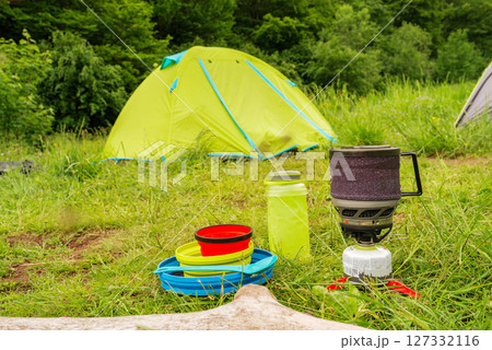 Camping utensils and kitchen. Camping camp with tents and utensils. Camping kitchen against the background of a tent. Cooking outdoors. 127332116