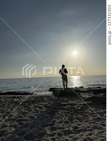silhouette of a fisherman at sea sunset calm. High quality photo 127332303