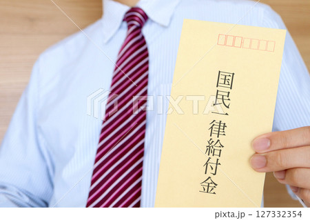スーツの男性が国民一律給付と書かれた封筒を持っている 127332354