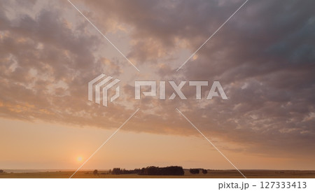 Time lapse. A Serene Sunset Over Expansive Fields Accompanied by a Dramatic and Colorful Cloudscape 127333413