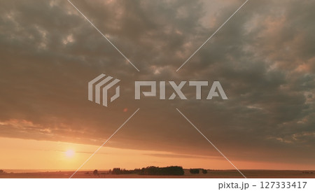 Time lapse. A stunningly beautiful sunset over expansive fields set against a cloudy sky backdrop Time lapse. A stunningly beautiful sunset over expansive fields set against a cloudy sky backdrop 127333417