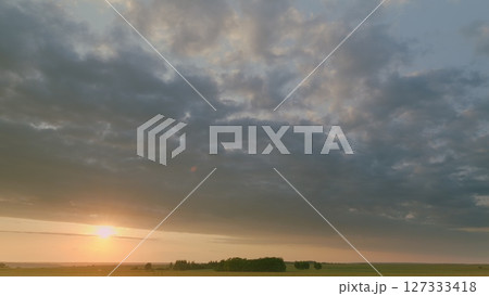 Time lapse. Witness a stunning sunset illuminating green fields and cloudy skies, inspiring peace at dusk 127333418