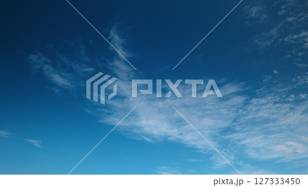 Time lapse. An expansive and captivating clear blue sky adorned with soft, fluffy clouds floating by 127333450