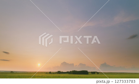 Time lapse. A Serene Sunset Over Beautifully Lush Green Fields Creates an Inspiring and Peaceful Atmosphere Time lapse. A Serene Sunset Over Beautifully Lush Green Fields Creates an Inspiring and Peaceful Atmosphere 127333783