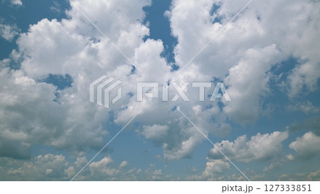 Time lapse. Fluffy white clouds drift lazily in a bright, vibrant blue sky above us, creating a stunning visual Time lapse. Fluffy white clouds drift lazily in a bright, vibrant blue sky above us, creating a stunning visual 127333851