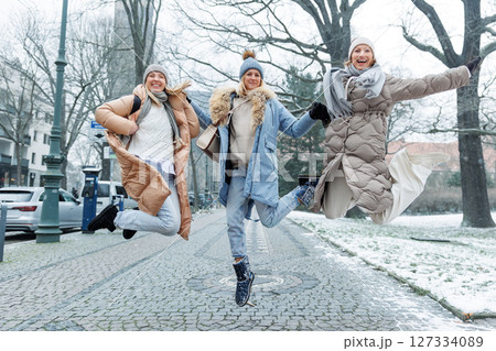 Three cheerful young adult women friend walk Magdeburg street old european uk german town city street enjoy having fun laughing cold winter day together. Female persons friendship celebration weekend 127334089