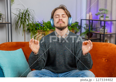 Bearded man listening music, breathes deeply meditating with concentrated thoughts peaceful at home 127334402