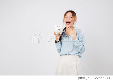 Happy woman holding piggy bank smiling excited with piggy save money win and showing success in finance, bank planning, and smart investment. isolated studio white background Happy woman holding piggy bank smiling excited with piggy save money win and showing success in finance, bank planning, and smart investment. isolated studio white background 127334953