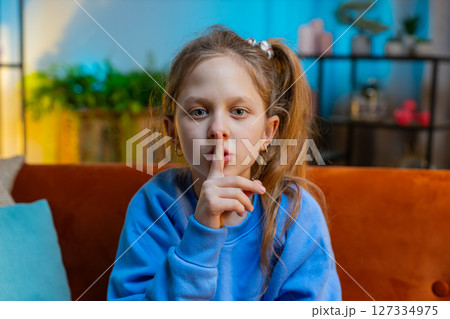 Preteen child girl presses finger to lips makes silence hush sign do not tell gossip secret, quiet 127334975