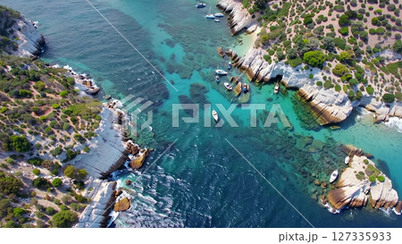 Aerial view capturing pristine white boats anchoring near verdant mediterranean island, transparent turquoise waters surrounding dramatic white rocky coastline Aerial view capturing pristine white boats anchoring near verdant mediterranean island, transparent turquoise waters surrounding dramatic white rocky coastline 127335933