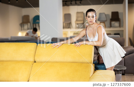 Adult happy smiling female touching sofa in the furniture store before buying 127337600