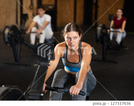 Woman in top exercising on rowing machine 127337636
